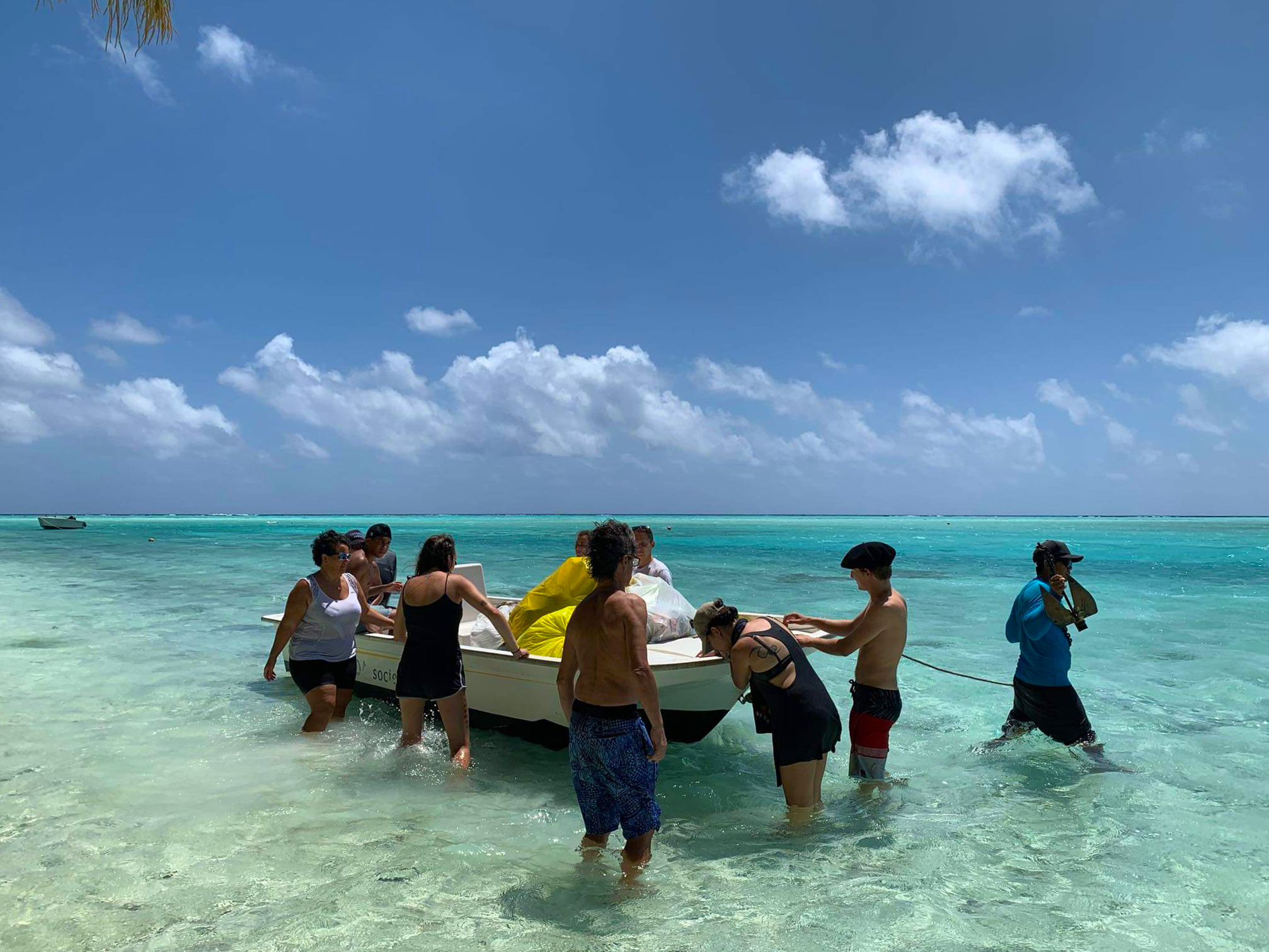 ten people standing around a boat in shallow water